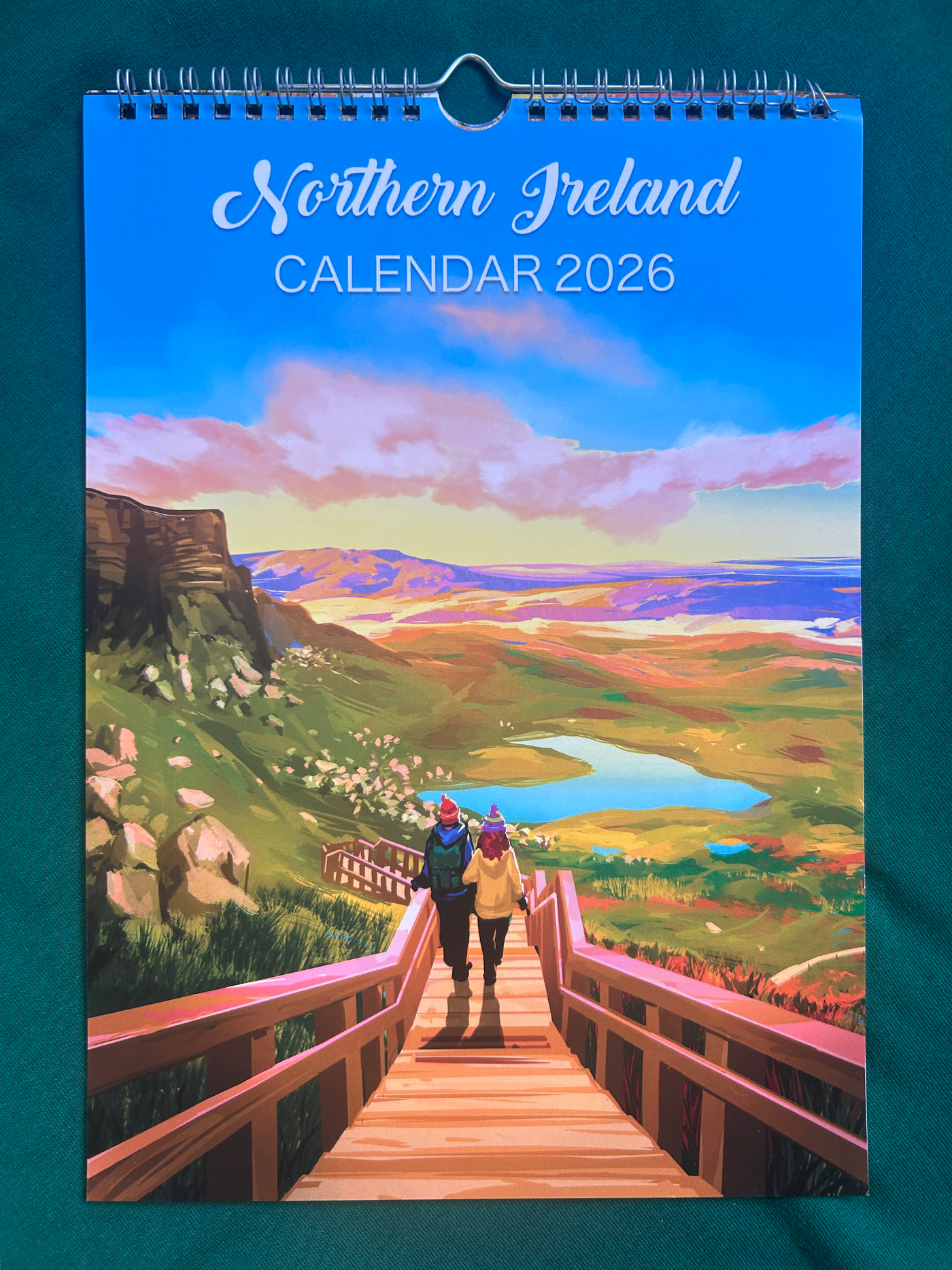 Calendar cover for 2026 featuring a scenic view of Northern Ireland with two people on a wooden bridge.